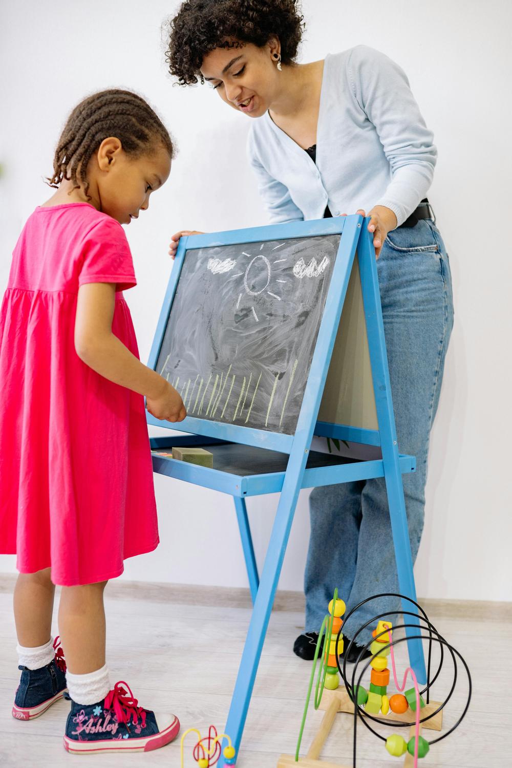 A therapist guiding a child at a drawing easel