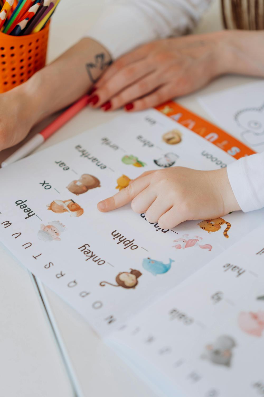 A child pointing to pictures in a learning workbook with a caregiver